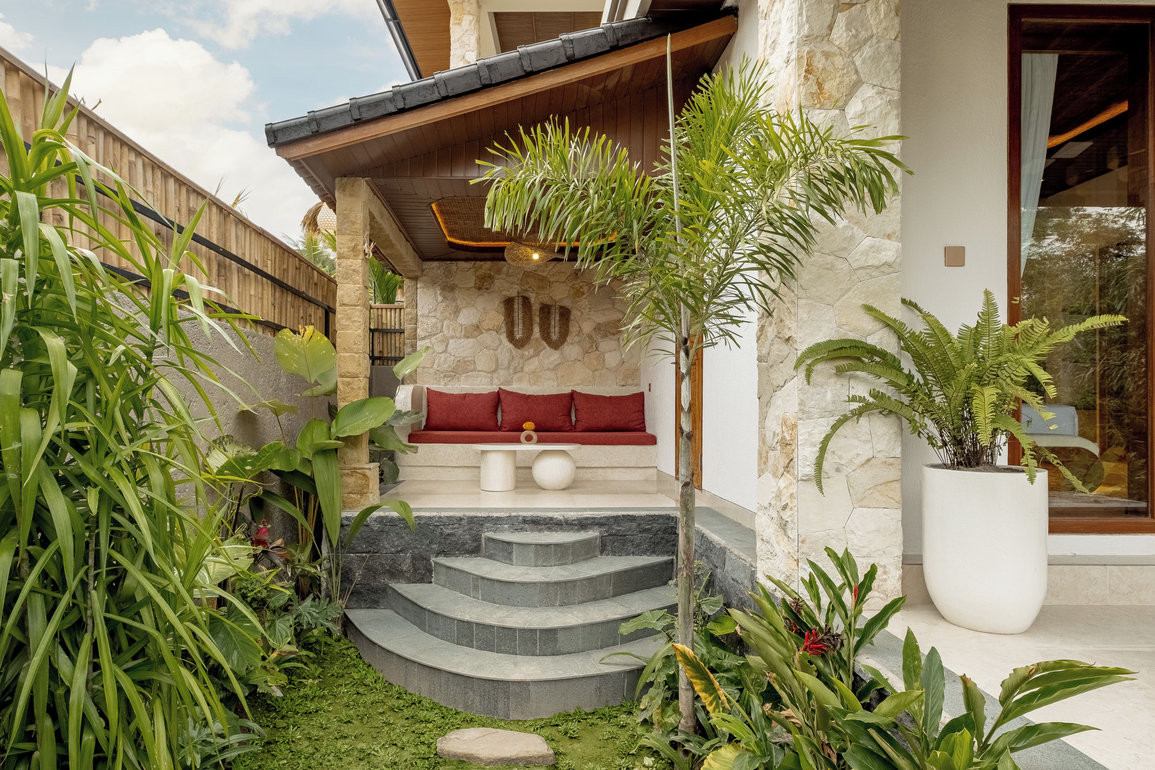 Una casa moderna con fachada de piedra, una terraza de madera y un banco rojo.