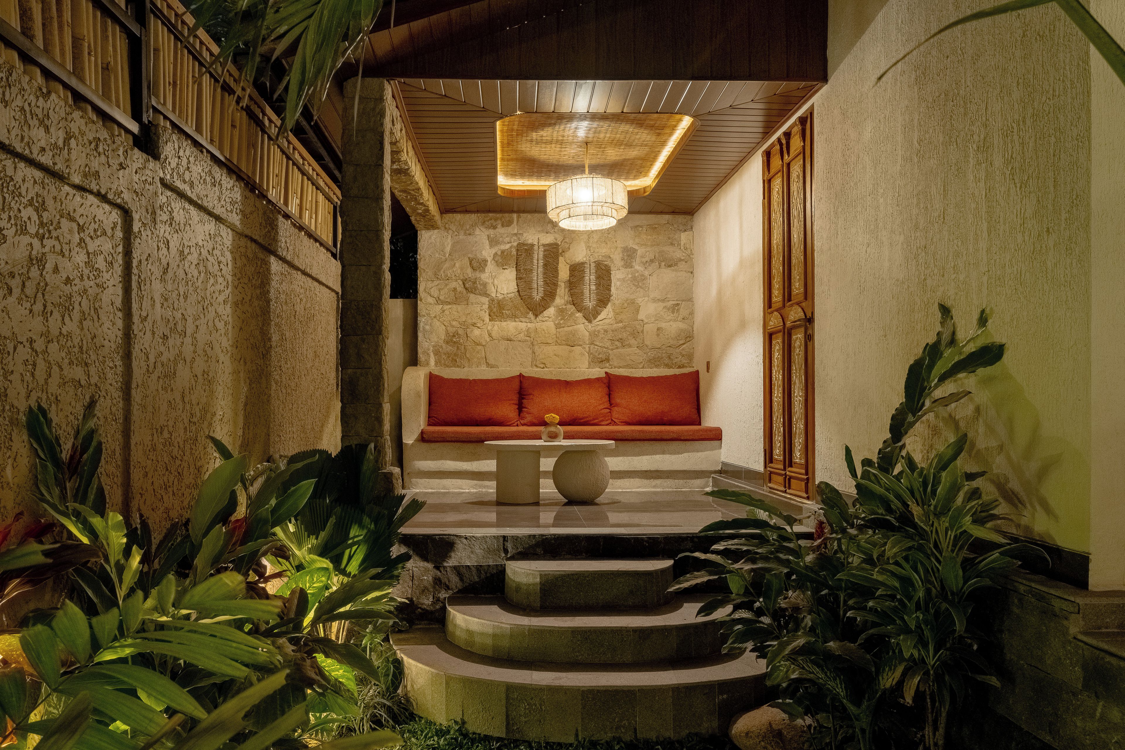 A stone-walled room with a bench, a table, and a hanging light fixture.