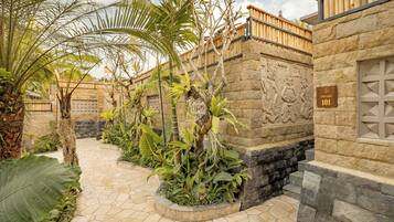 A stone pathway leading to a building with a wooden fence and a stone wall with carvings.