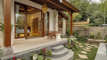 A covered outdoor area with a stone wall, a wooden pergola, and a seating area with a table and chairs.