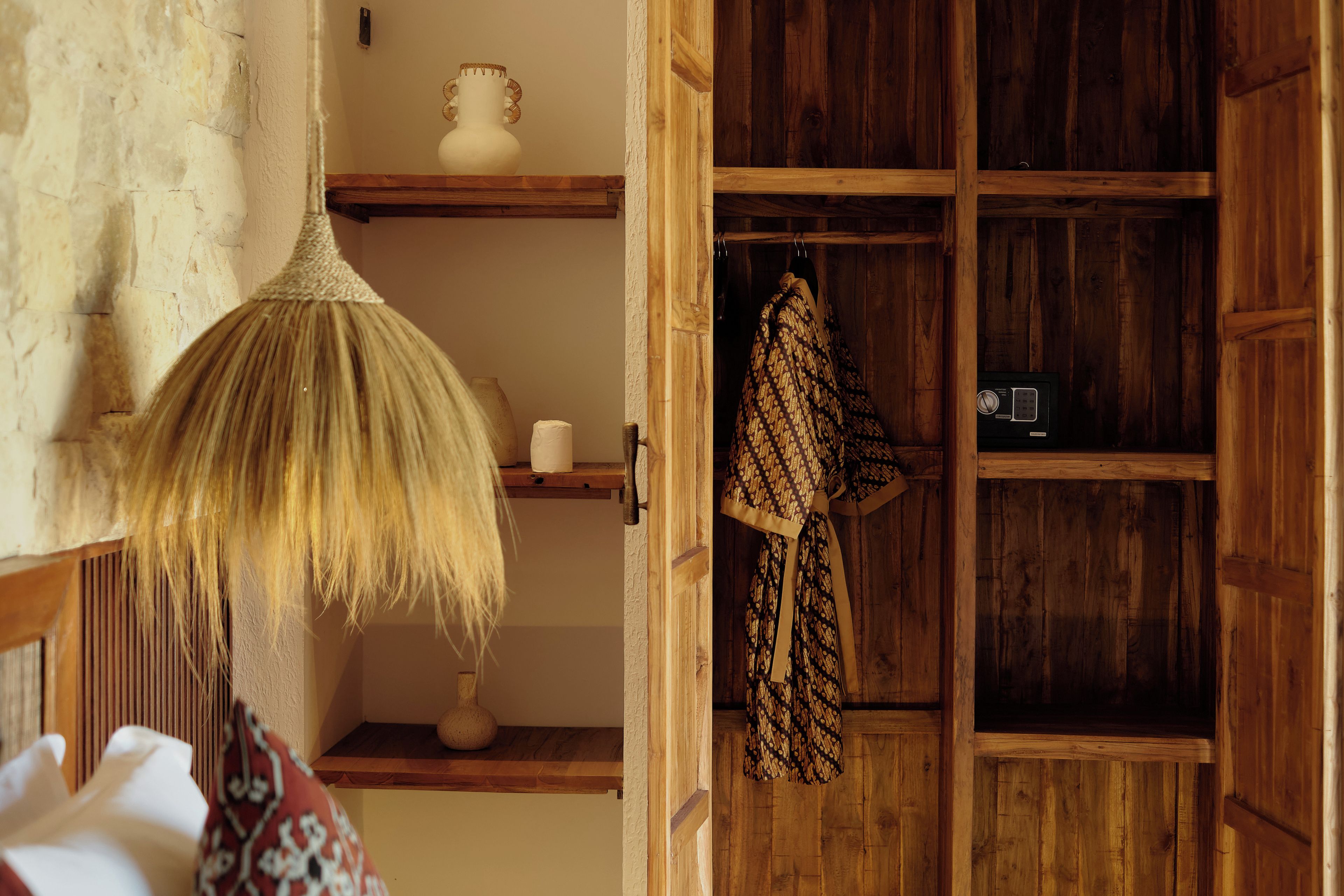 Una habitación con un armario de madera, una lámpara colgante y un tejido estampado.