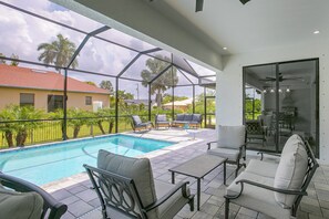 Ein überdachter Außenbereich mit Pool, Sitzgelegenheiten und Blick auf die Nachbarschaft.