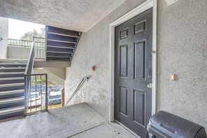 A concrete exterior with a dark door, a metal staircase, and a trash bin. - Gateway to UF & Dtwn Gainesville! Condo w/ Pool (Gainesville)