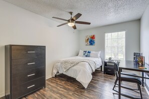 A bedroom with a bed, a desk, a chair, a wardrobe, a ceiling fan, and a window with blinds. - Gateway to UF & Dtwn Gainesville! Condo w/ Pool (Gainesville)