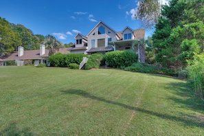 A large, two-story house with a well-maintained lawn and a covered patio area. - Luxury, 2 Master Suites, Fire Pit, Kayaks (Milledgeville)