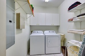 A laundry room with two white Whirlpool washers, a shelf with folded towels, and a metal rack with a bag. - Luxury, 2 Master Suites, Fire Pit, Kayaks (Milledgeville)