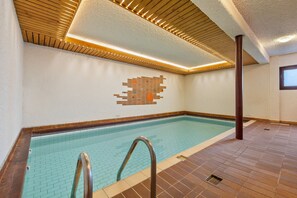 A swimming pool with a tiled wall and a wooden ceiling. - Grand-Place 09 - 5 people - cozy retreat & pool (Haute-Nendaz)