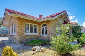 A stone house with a red-tiled roof, two windows with shutters, and a small garden with a tree and a wooden stump. - Hidden Gem Near Ocean Center, Water Park & Theater (Daytona Beach)