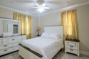 A hotel room with a bed, a dresser, a nightstand, a lamp, and a ceiling fan. - Hidden Gem Near Ocean Center, Water Park & Theater (Daytona Beach)