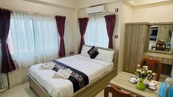 Una habitación de hotel con una cama, un escritorio, una silla, un ventilador de techo y cortinas.