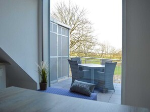 A balcony with a table and chairs, a potted plant, and a view of trees. - Dream Crown Sky Blue (Schortens)