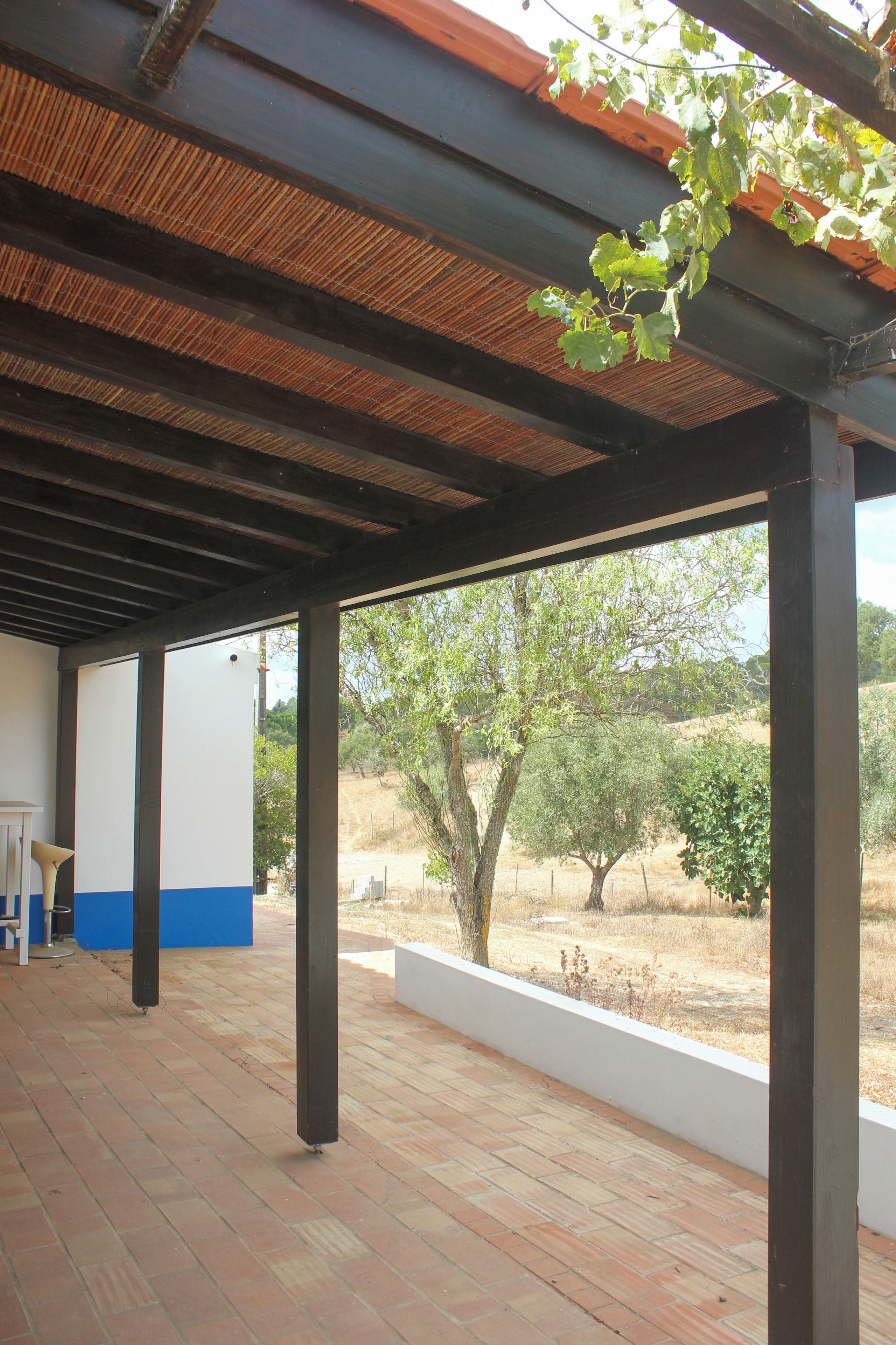 An outdoor covered patio area with a view of a dry landscape and trees.