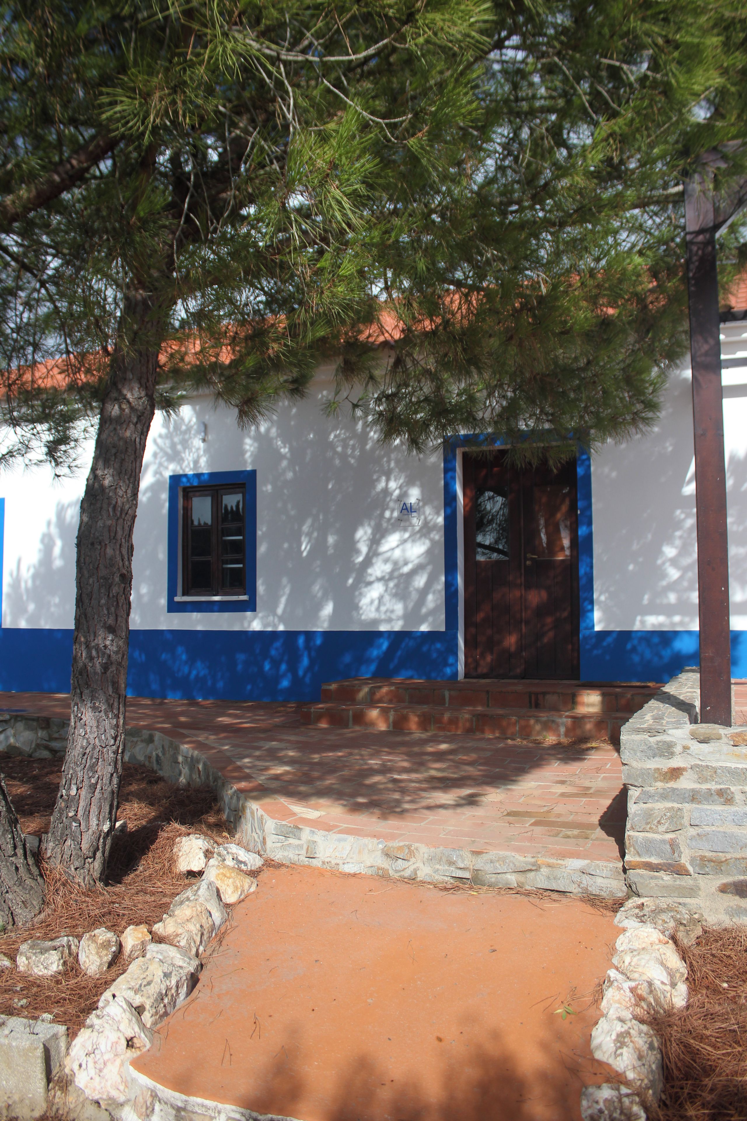 Un edificio con fachada blanca y detalles azules, una puerta de madera y una ventana.