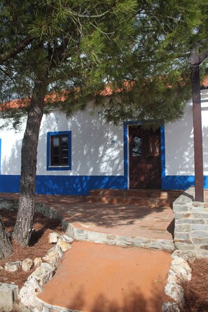 Un edificio con fachada blanca y detalles azules, una puerta de madera y una ventana.