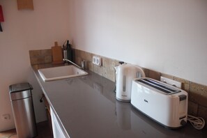 A kitchen with a sink, a kettle, and a toaster on the countertop.