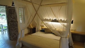 Una habitación con una cama bajo un dosel, un armario de madera y una mesita.
