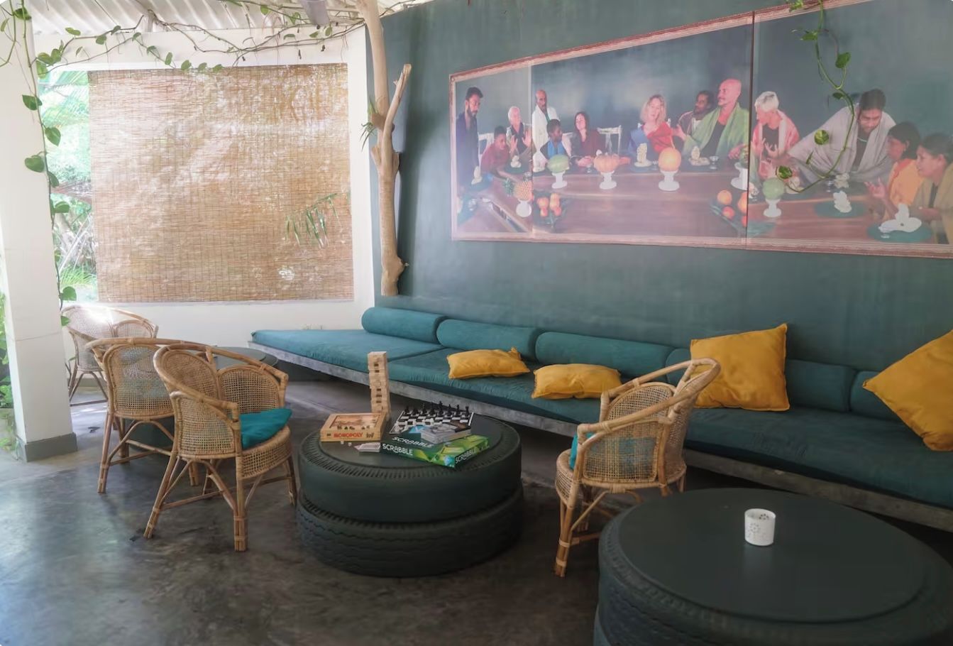 Quarto com sofá verde, cadeiras de vime, mesa de centro feita com pneu e um quadro na parede.