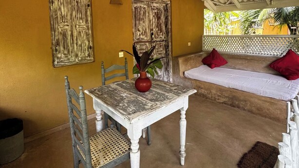 Una habitación con una mesa, sillas, una cama y obras de arte en las paredes.
