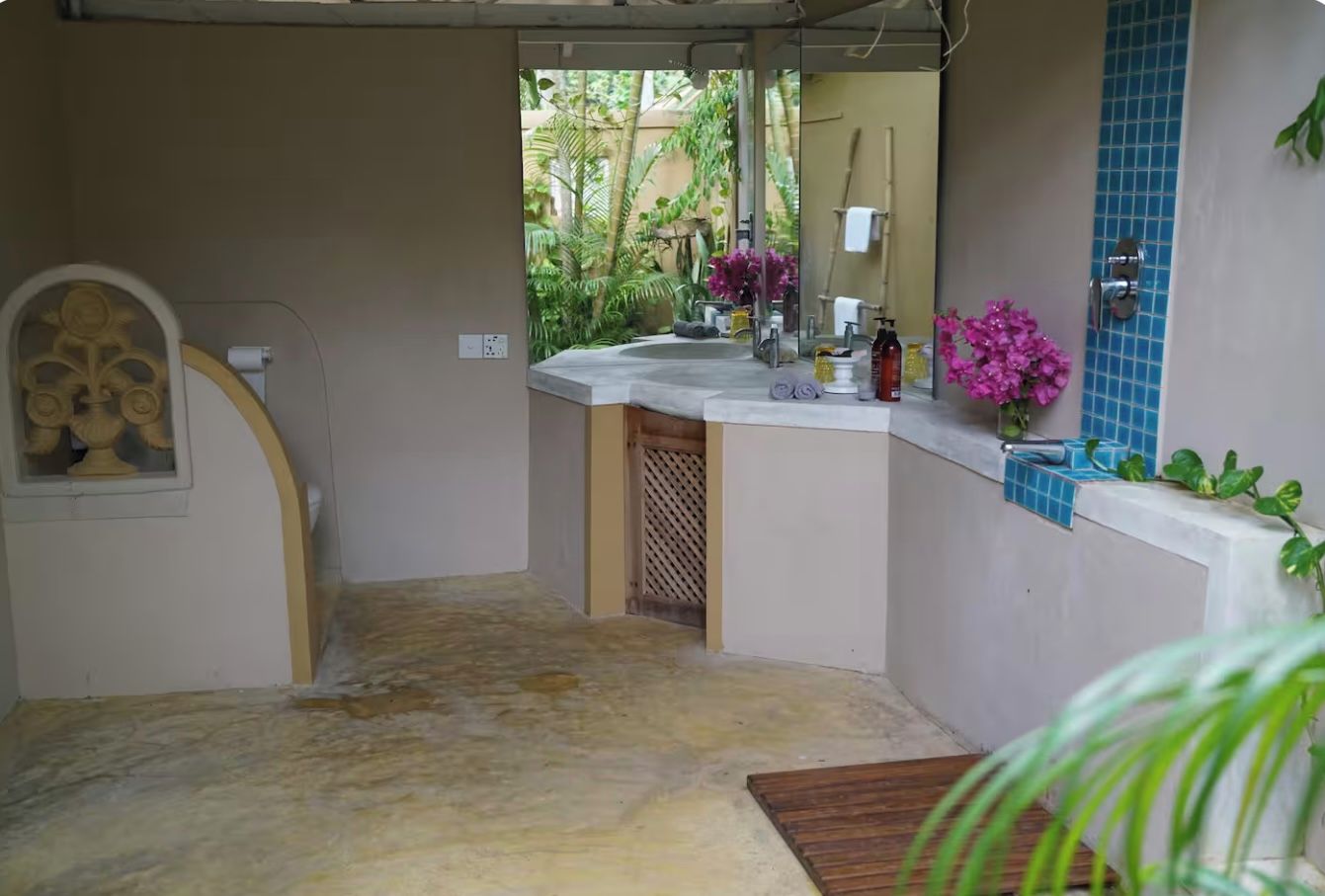 Casa de banho com lavatório, espelho e vista para um jardim.