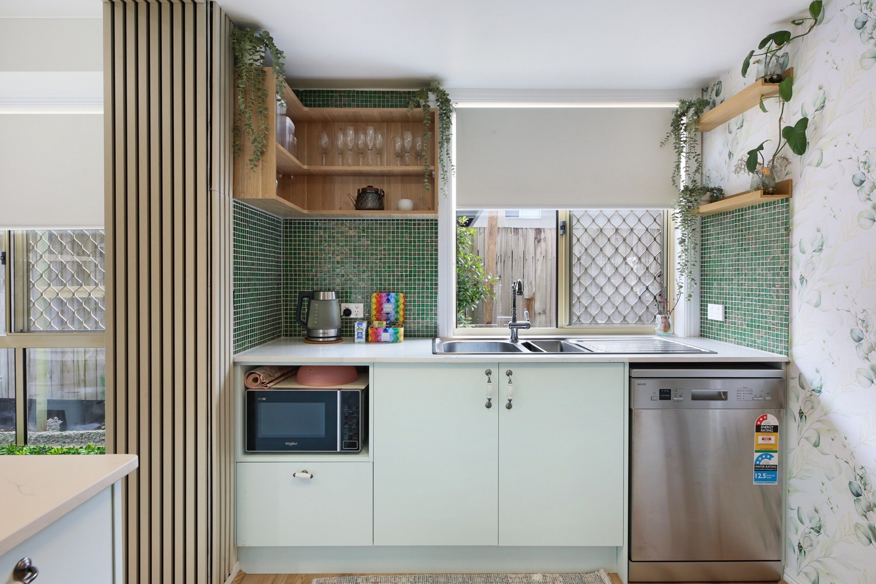 A modern kitchen with a built-in dishwasher, a kettle, and a microwave.