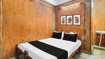 Habitación de hotel con pared de paneles de madera, cama con ropa de cama blanco y negro, y un baño pequeño con lavamanos.