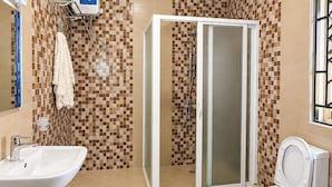 A bathroom with a shower, toilet, sink, and a tiled wall with a checkered pattern. - Serene Harmony Homes (Kampala)
