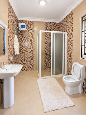 Une salle de bain avec douche, toilettes, lavabo et un mur carrelé à motifs à carreaux.