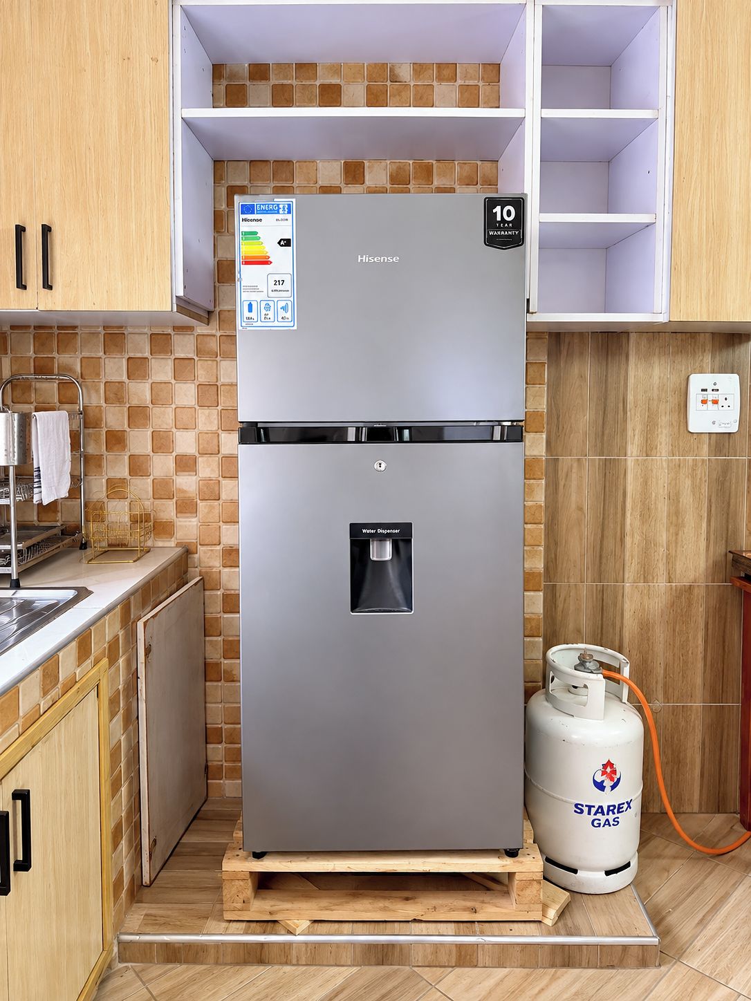 A stainless steel refrigerator with a water dispenser and a gas cylinder.
