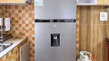 A stainless steel refrigerator with a water dispenser and a gas cylinder.