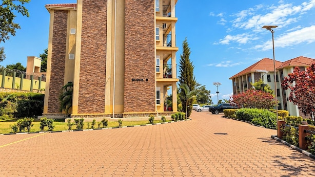 A multi-story building with a brick facade, labeled 'BLOCK B,' and a paved driveway leading to it. - Serene Harmony Homes (Kampala)