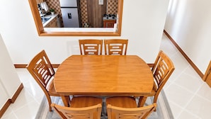 A dining area with a wooden table and chairs, a rug, and a kitchen visible through a window. - Serene Harmony Homes (Kampala)