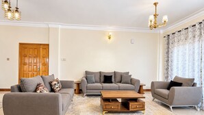 A modern living room with a sofa set, a coffee table, and a chandelier. - Serene Harmony Homes (Kampala)