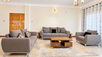 A modern living room with a sofa set, a coffee table, and a chandelier.