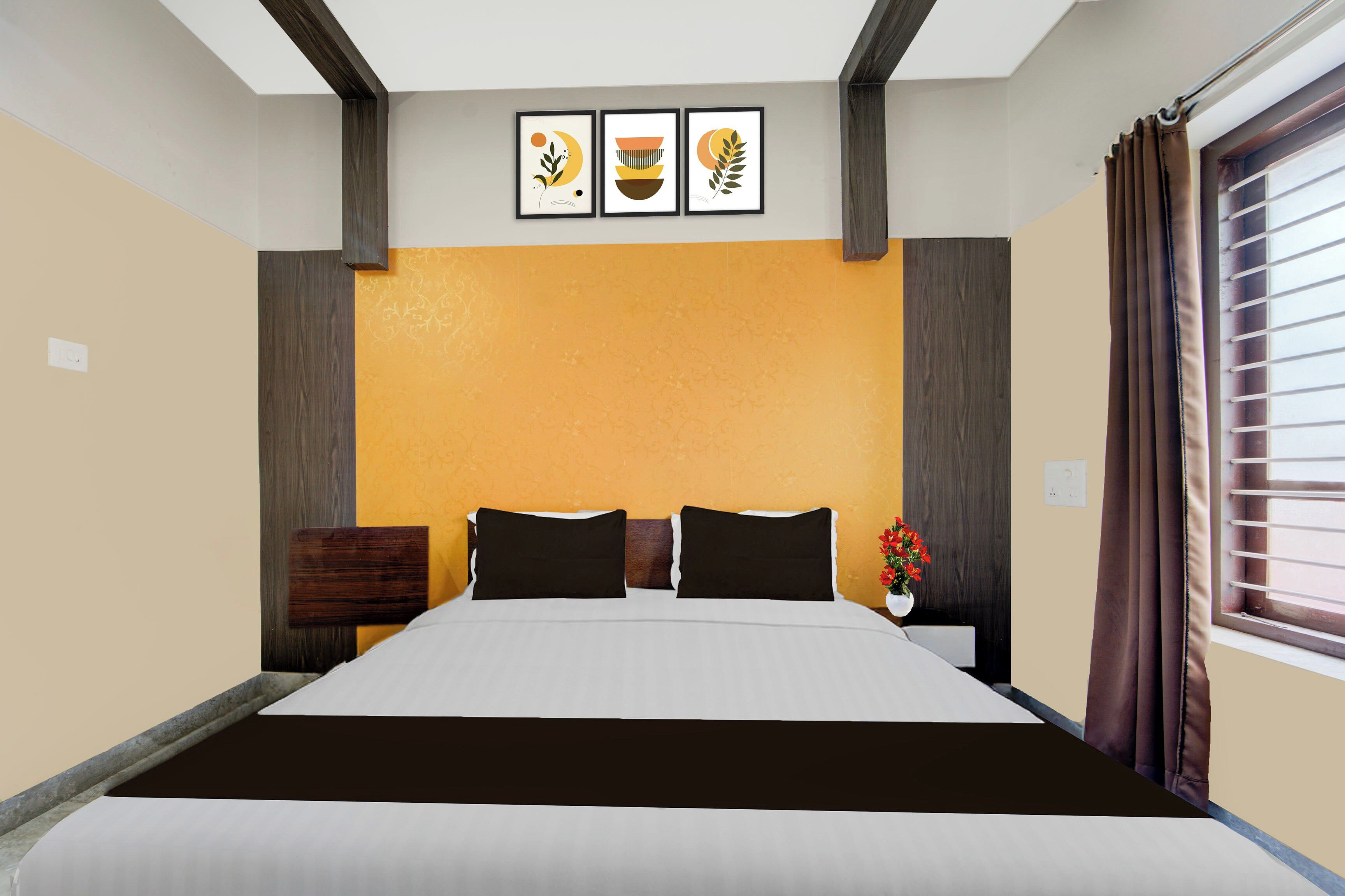 Ein Hotelzimmer mit einem Bett, einem Nachttisch, einer Vase mit Blumen und drei gerahmten Bildern an der Wand.