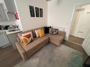 Ein modernes Wohnzimmer mit einem beigefarbenen Ecksofa, einem gemusterten Teppich und Wanddekoration.