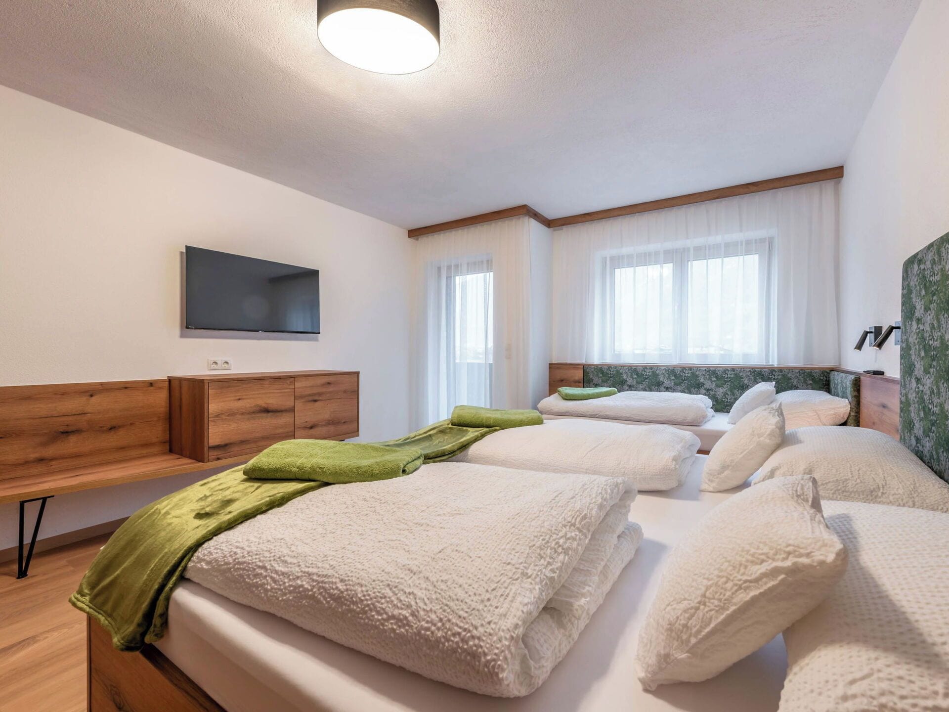A hotel room with a bed, a TV, a desk, and a window.