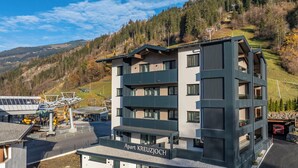 Un hotel moderno a più piani, situato in una zona montana con una seggiovia sullo sfondo.