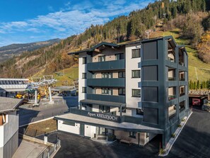 A multi-story hotel with a modern design, located in a mountainous area with a ski lift in the background. - Beautiful apartment for 5 guests with WIFI, TV and balcony (Zell Am Ziller)