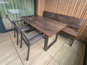 Una mesa de comedor moderna con bancos, una puerta de cristal y una pared de madera.