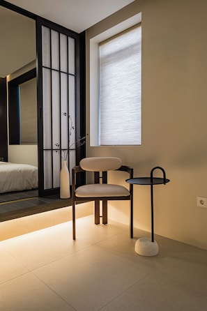 A room with a bed, a chair, a small table, and a window with blinds. - Grida Hongdae (Seoul)