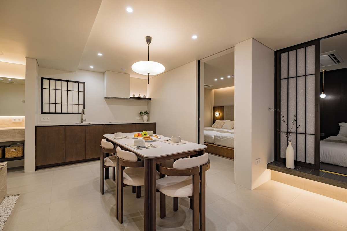 A modern interior with a dining area, kitchen, and a bedroom.