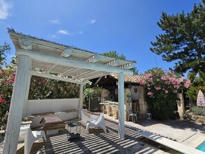 Ein überdachter Außenbereich mit einer Pergola, Steinmauern und einem Pool.