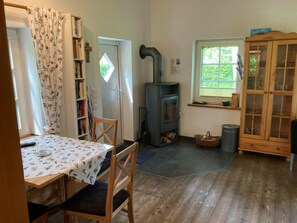 Una habitación acogedora con una mesa de madera, sillas, una estantería, una chimenea y un armario.