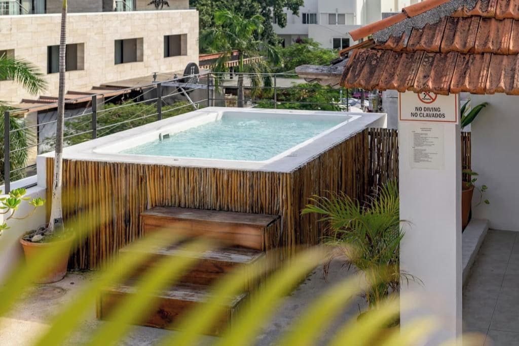 A rooftop pool with a bamboo enclosure, a no diving sign, and a tiled roof.