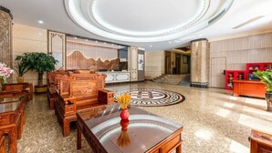 A lobby with a circular ceiling design, a reception desk, and traditional wooden furniture. - Ruijing Hotel (Dongguan)