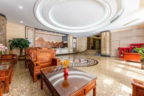 A lobby with a circular ceiling design, a reception desk, and traditional wooden furniture. - Ruijing Hotel (Dongguan)
