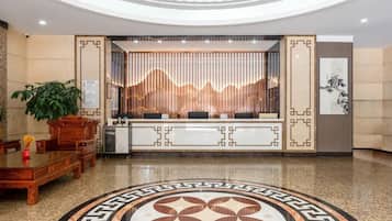 Zona de recepción de hotel con mostrador, área de descanso y una pared decorativa con diseño de montaña.