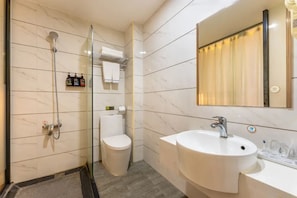 A modern bathroom with a glass-enclosed shower, a toilet, and a sink with a mirror above. - Ruijing Hotel (Dongguan)
