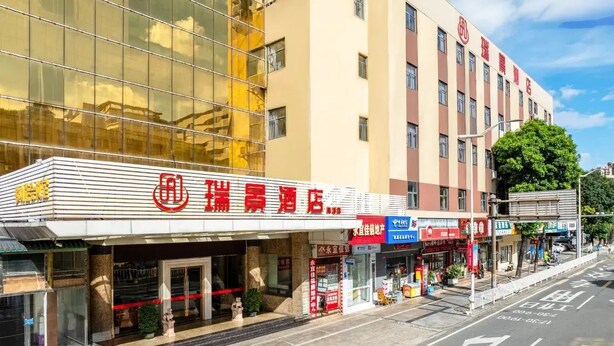 A hotel with a modern facade, multiple floors, and a variety of signage. - Ruijing Hotel (Dongguan)