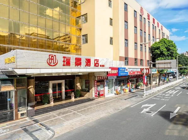 A hotel with a modern facade, multiple floors, and a variety of signage. - Ruijing Hotel (Dongguan)